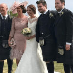 Happy wedding party outdoors with bride and groom in traditional attire.