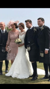 Happy wedding party outdoors with bride and groom in traditional attire.