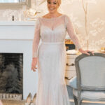 Beautiful bride in a lace wedding dress with a fascinator in a classic room setting.