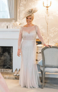 Beautiful bride in a lace wedding dress with a fascinator in a classic room setting.