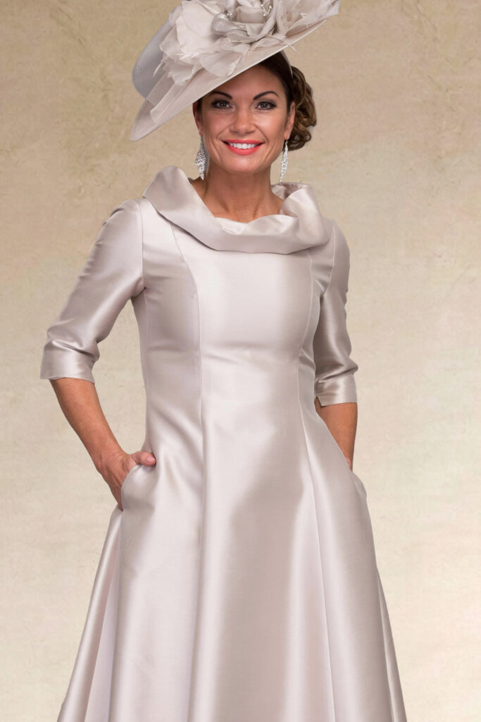 Woman in an elegant silver satin dress and matching hat.
