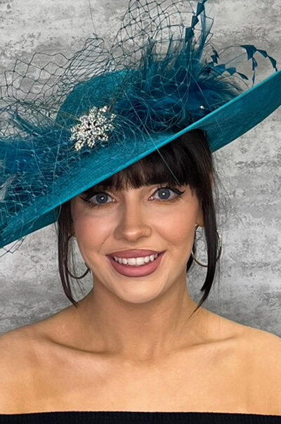 Stylish blue hat with feathers and decorative brooch for special occasions.