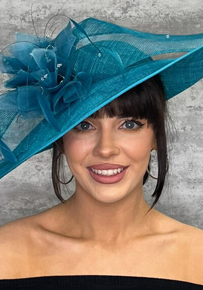 Elegant teal hat with feather embellishments for special occasions.
