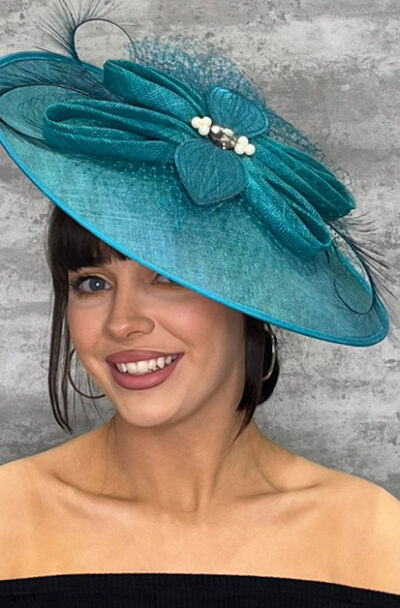 Elegant teal hat with feather quill and pearl accents for special occasions.