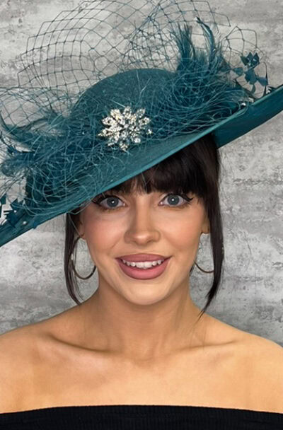 Elegant teal hat with feathers, netting, and diamante brooch for special occasions.