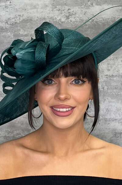 Green upturned hat with floral and feather details for formal occasions.
