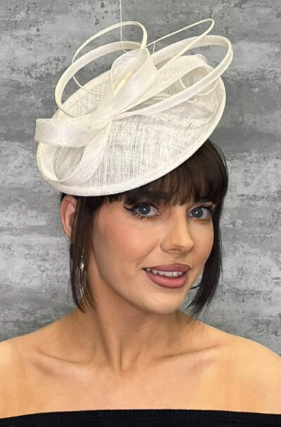 Woman wearing a stylish white fascinator hat with loops and netting detail.