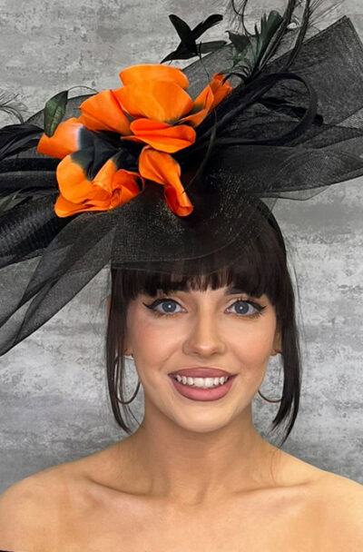 Elegant black hat with orange crin waves, feathers, and tulle for special occasions.