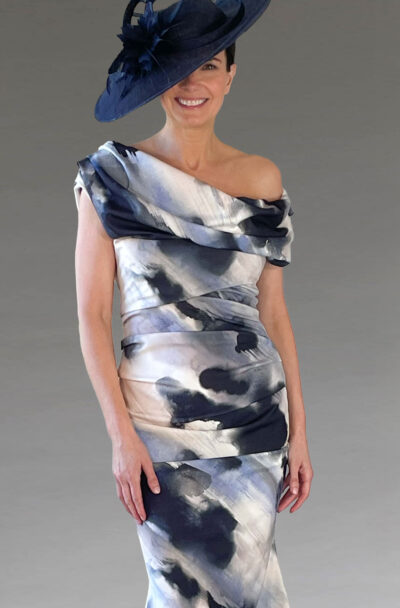 A smiling woman in a patterned dress and navy hat.