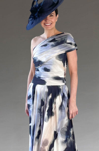 A smiling woman wearing a blue hat and patterned dress.