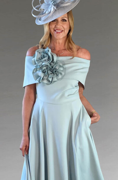 A smiling woman in a light blue occasionwear dress.