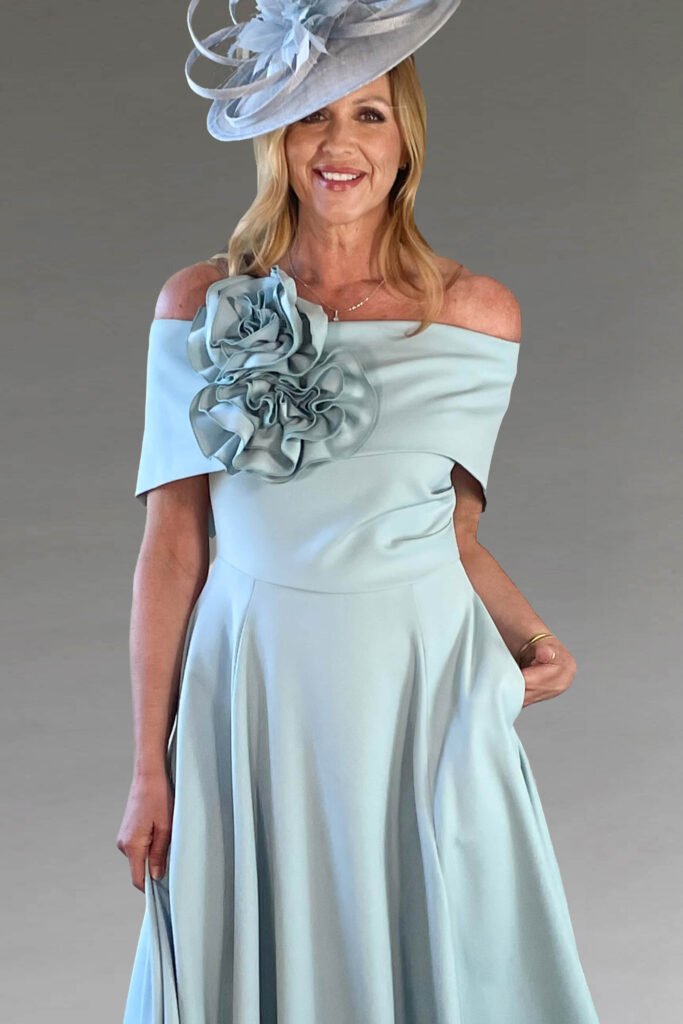 A smiling woman in a light blue occasionwear dress.
