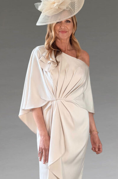 Woman in an elegant cream one-shoulder dress and hat.