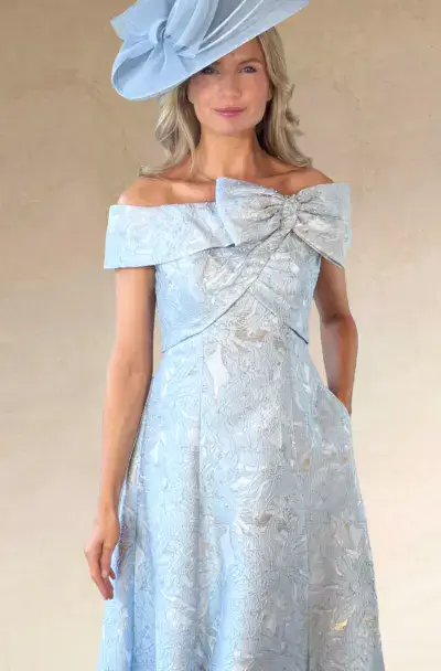 Woman wearing an elegant light blue dress and matching hat.