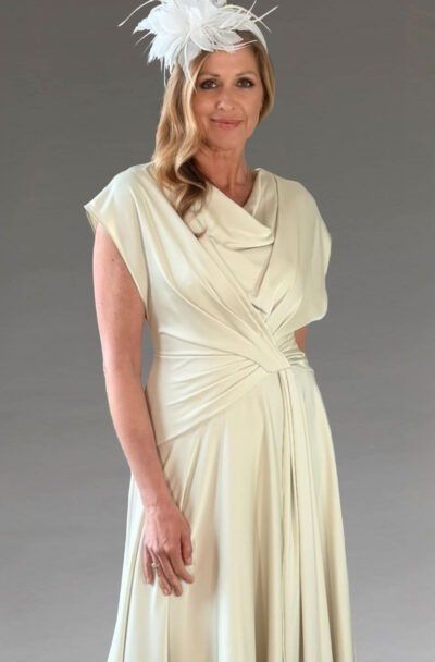 Elegant woman in a cream dress and white fascinator.