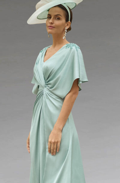 A woman in an elegant mint green dress and hat.