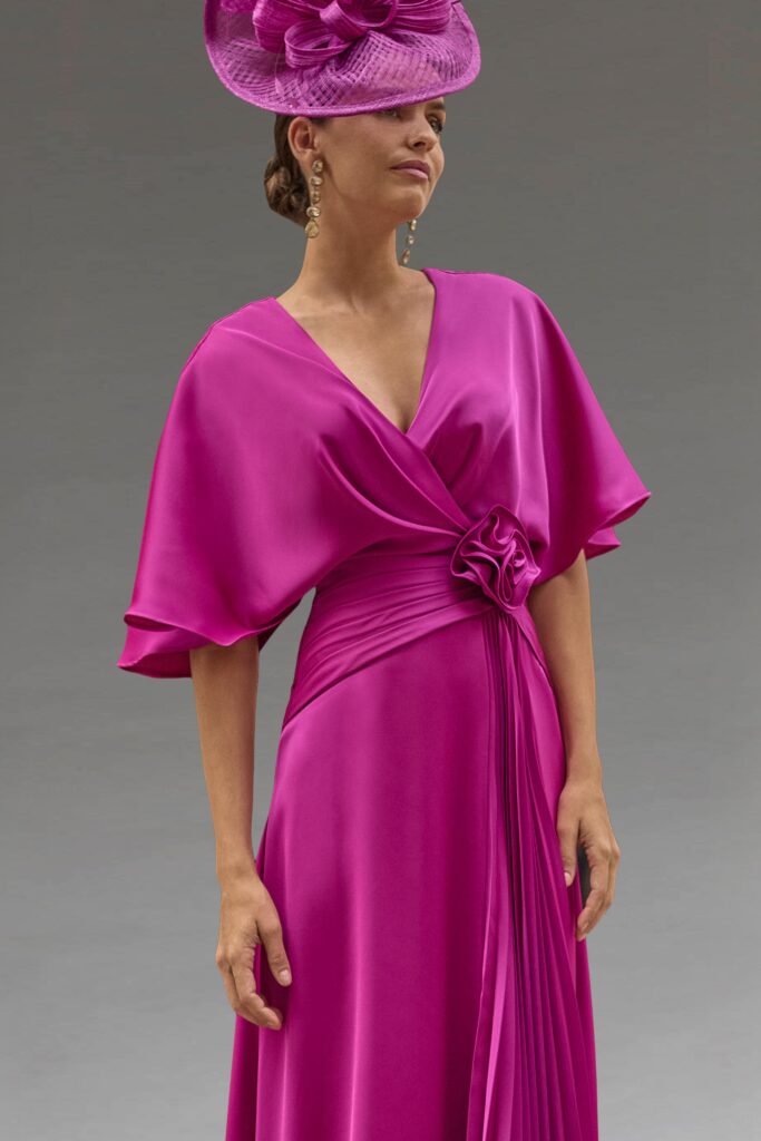 Elegant woman wearing a vibrant fuchsia dress and matching hat.