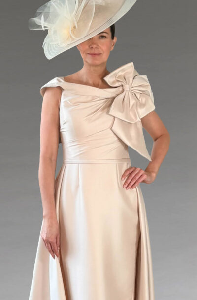 Woman in an elegant cream dress with a matching hat.