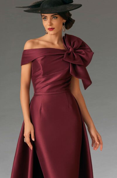 A woman in an elegant burgundy gown and black hat.