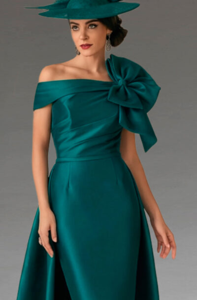 A woman in an elegant emerald green dress and hat.