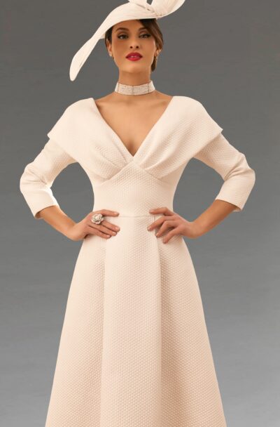 A woman in an elegant cream dress and matching hat.