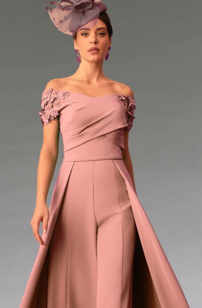 A woman in a pink formal jumpsuit and fascinator.