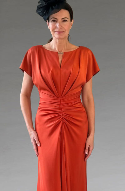 Woman in an elegant orange ruched dress and black fascinator.