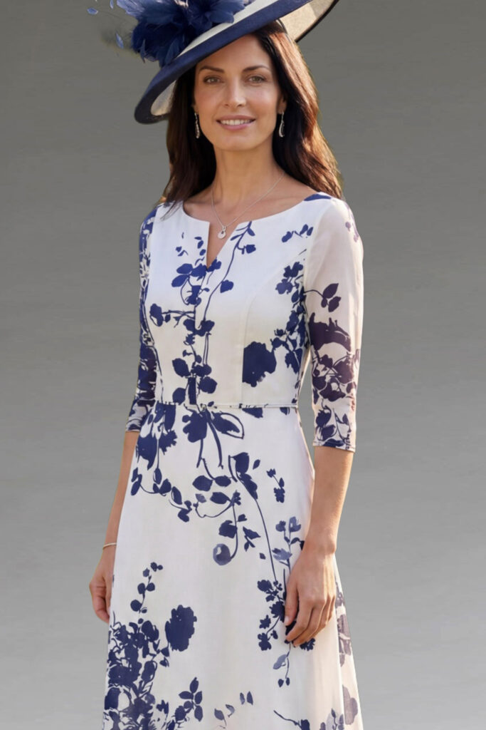 A woman modelling a floral dress and navy hat.