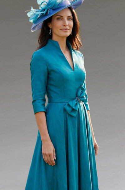 A woman in an elegant teal dress and blue hat.