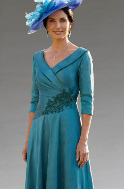 A woman in a teal dress and matching blue fascinator.