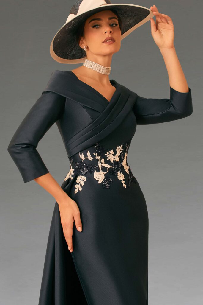 An elegant woman in a navy dress and hat.