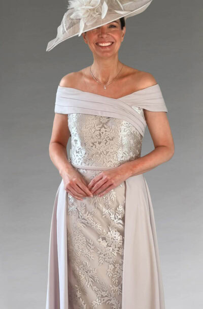 A smiling woman in an elegant grey dress and fascinator.