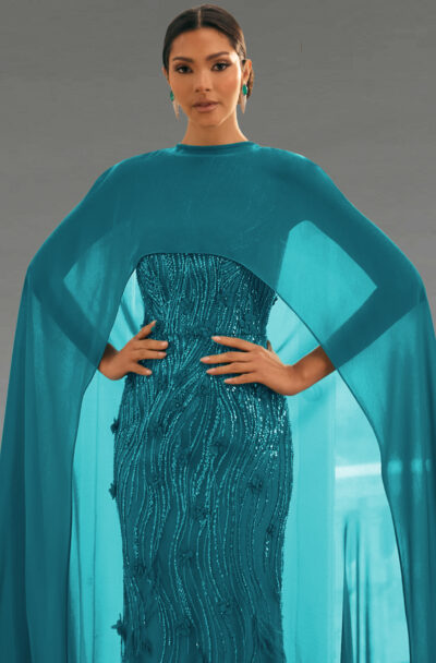 A woman in an elegant teal gown with a cape.