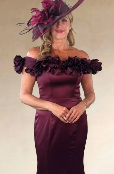 A woman in a burgundy dress and matching fascinator hat.