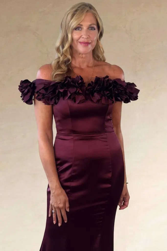 A woman wearing a dark red off-the-shoulder evening gown.