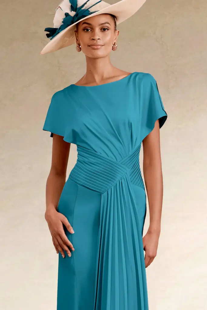 Woman in an elegant teal dress and cream fascinator hat.